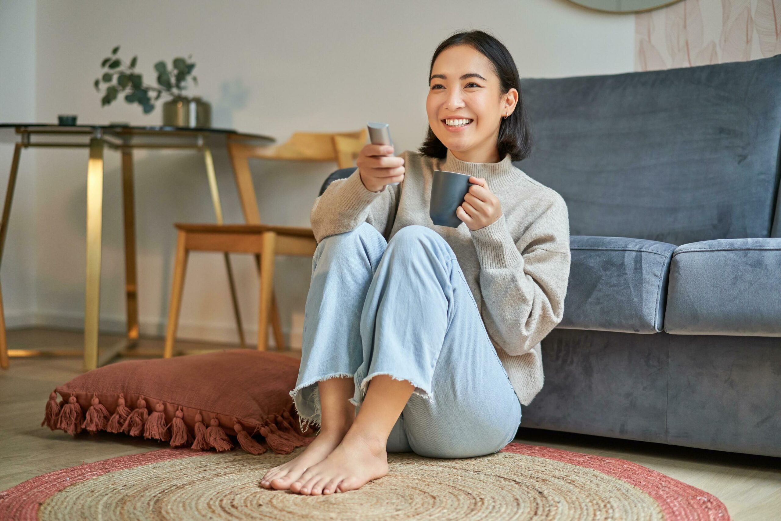 Lady sitting on a floor with a cup smiling